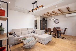 A modern living room with a sectional sofa, a glass coffee table, and a dining area with a wooden table and chairs. - Seaview Apartment Kostrena Two (Kostrena)