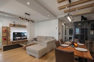 A modern living room with a sofa, dining table, and TV.