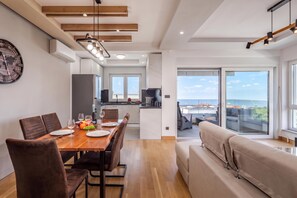 A modern kitchen with a dining area, a sofa, and a view of the city. - Seaview Apartment Kostrena Two (Kostrena)