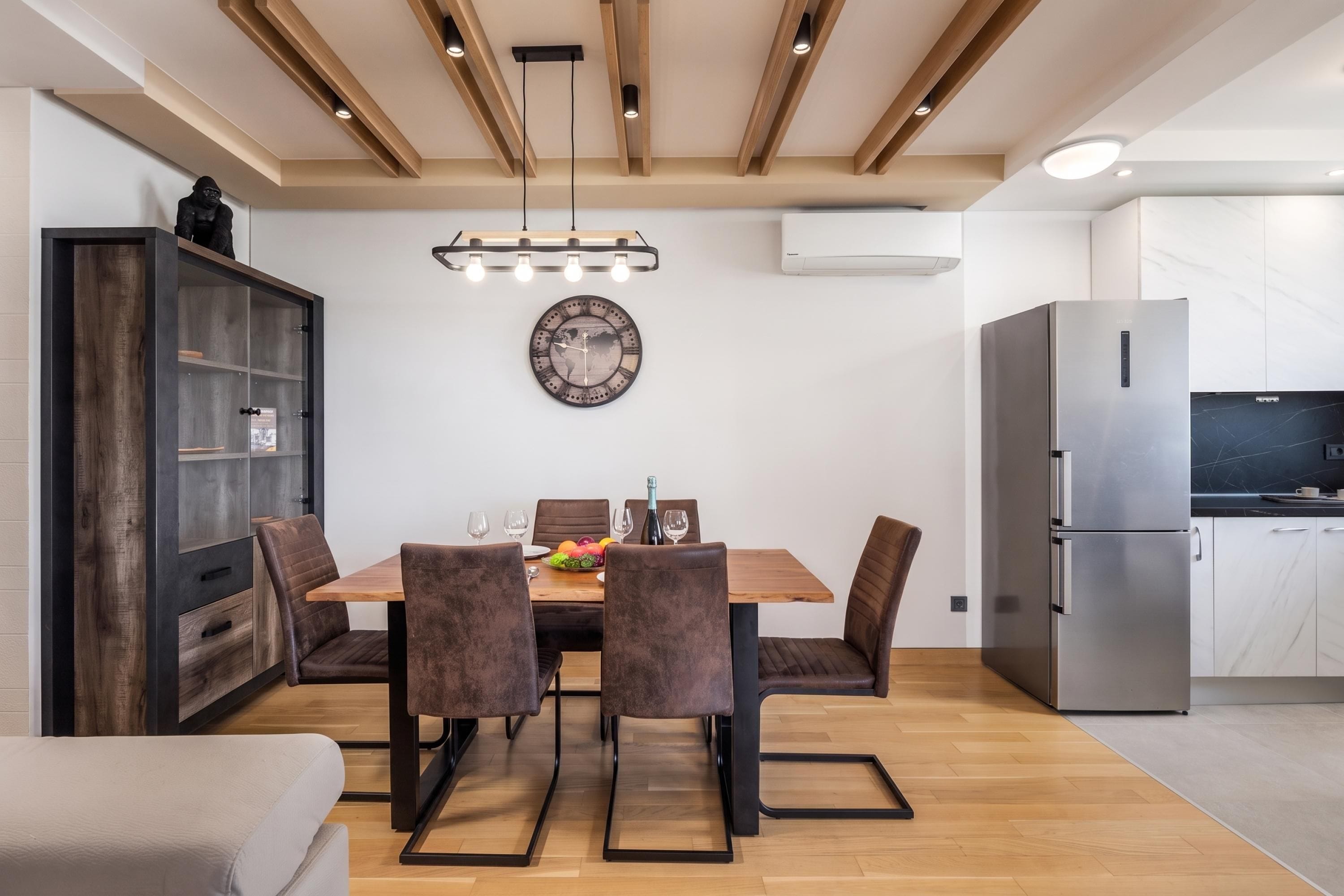 Un espace repas moderne avec une table en bois, des chaises rembourrées et une horloge murale décorative.