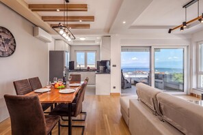 Ein stilvoller Essbereich mit einem Holztisch, Stühlen und Blick auf die Küche und den Balkon.