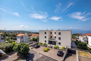 A modern building with a flat roof, a parking area, and a view of the sea. - Seaview Apartment Kostrena Two (Kostrena)