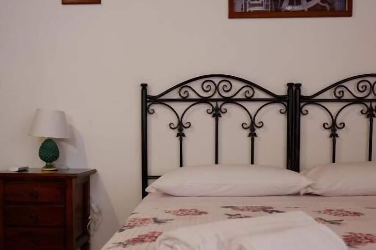 Ein Schlafzimmer mit einem Bett, einem Nachttisch, einer Lampe und einem gerahmten Bild an der Wand.