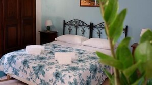 A bedroom with a bed, a nightstand, a potted plant, and an air conditioning unit. - Sikania Residence (Syracuse)