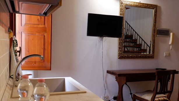 A kitchen with a wooden ceiling, a sink, a mirror, and a television. - Sikania Residence (Syracuse)