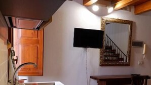 A kitchen with a sink, two bottles of water, a wooden table, and a chair. - Sikania Residence (Syracuse)