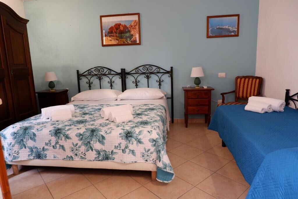 Quarto com uma cama, duas mesas de cabeceira, uma cadeira e duas quadros na parede.