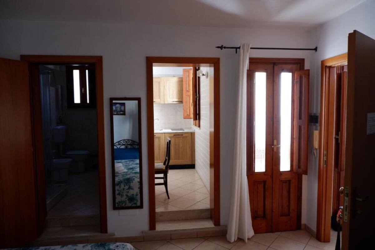 Ein Flur, der zu einem Schlafzimmer mit Bett, einem Badezimmer und einer Küchenzeile führt.