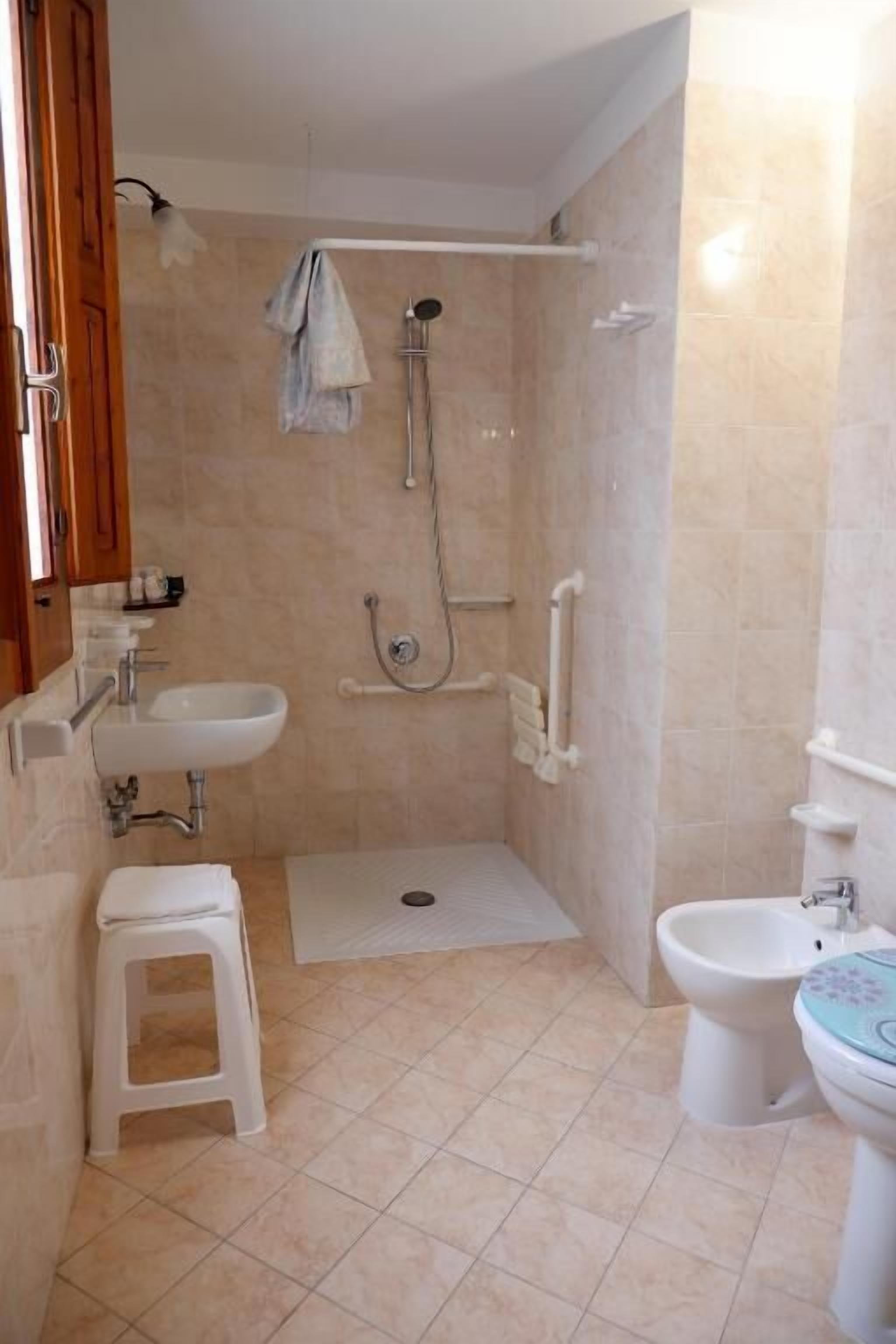 A bathroom with a shower, a sink, a toilet, and a bidet.