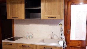 A kitchen with wooden cabinets, a sink, and a window. - Sikania Residence (Syracuse)