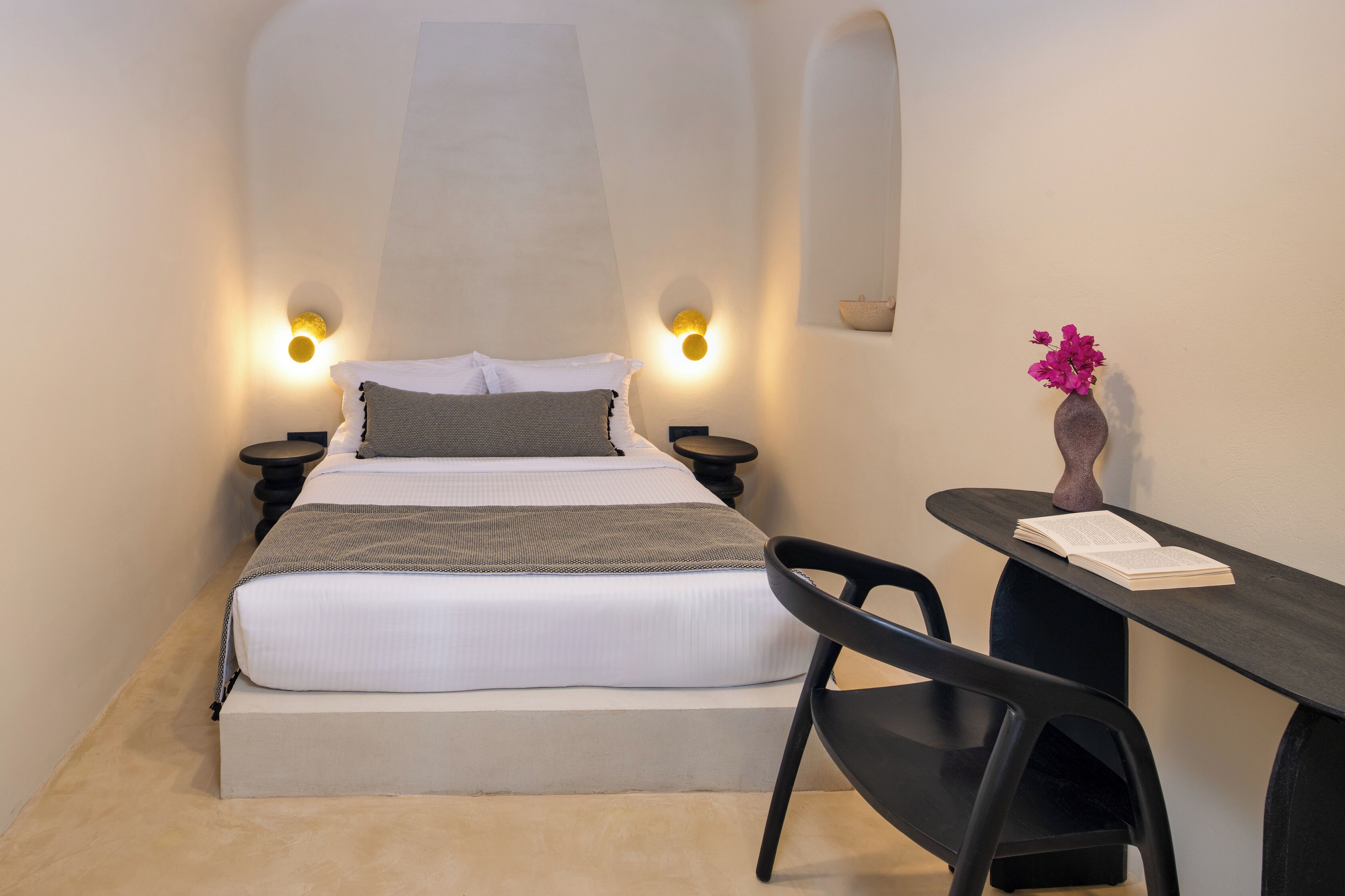 A bedroom with a bed, bedside tables, a desk, and a chair.