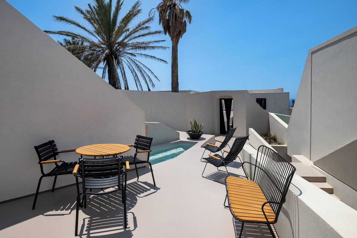 An outdoor patio with a pool, lounge chairs, and a table.