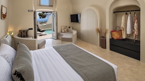 Un dormitorio con cama, zona de estar con vistas, televisor y armario.