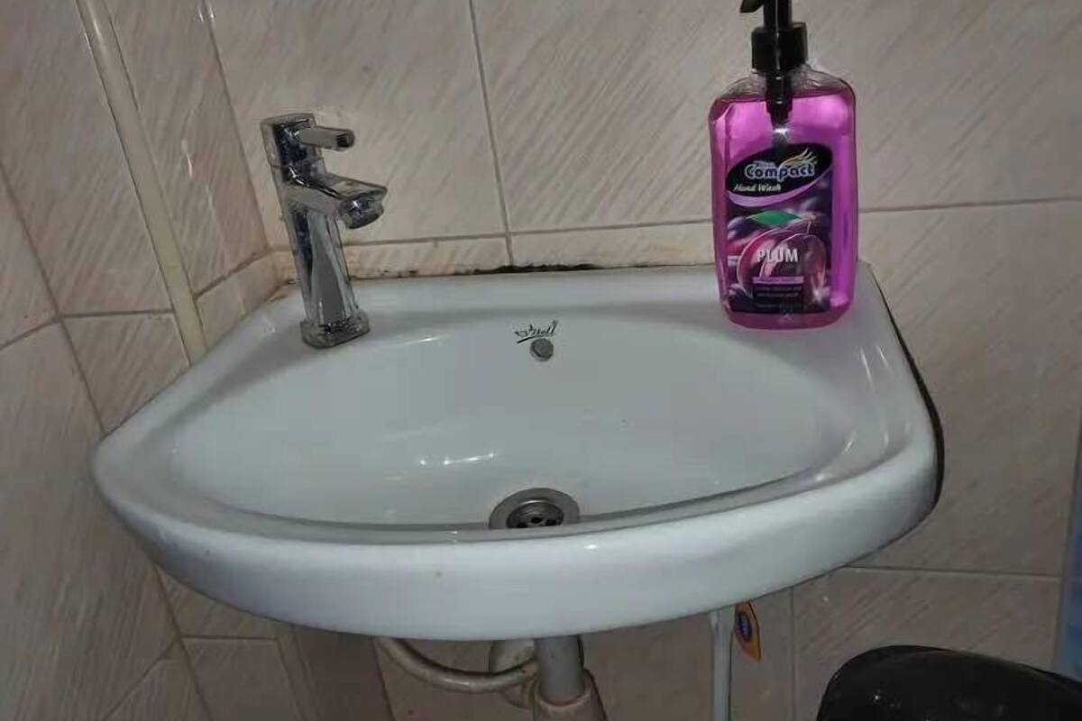 A white bathroom sink with a chrome faucet and a pink hand soap dispenser.
