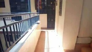 A corridor with tiled flooring, a metal railing on one side, and a door at the end. - Mountain view Spring (Nairobi)