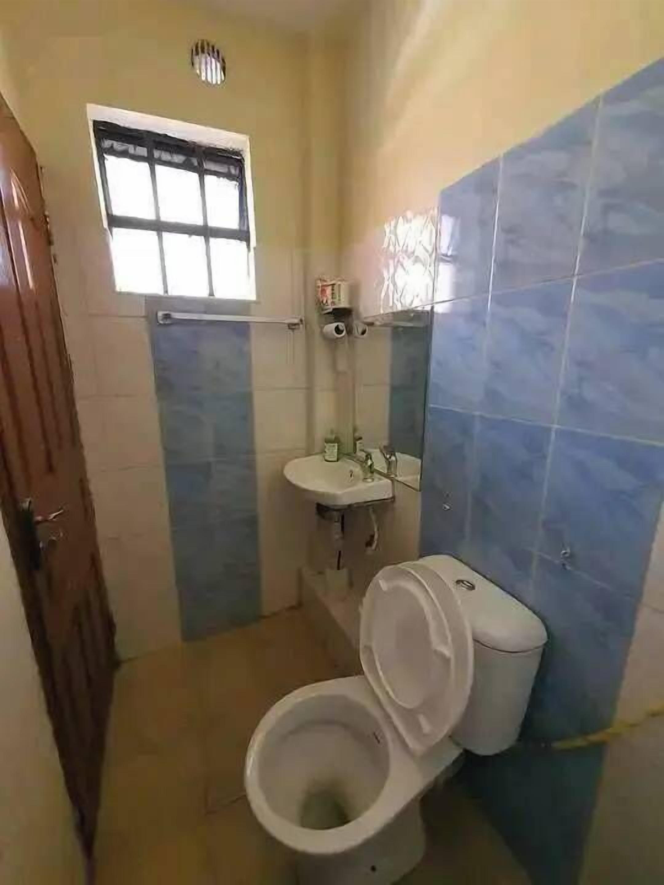 A small bathroom with a toilet, sink, and window.