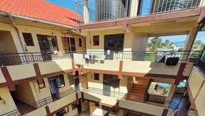 A multi-story residential building with balconies, a central courtyard with cars, and a view of the surrounding area. - Mountain view Spring (Nairobi)