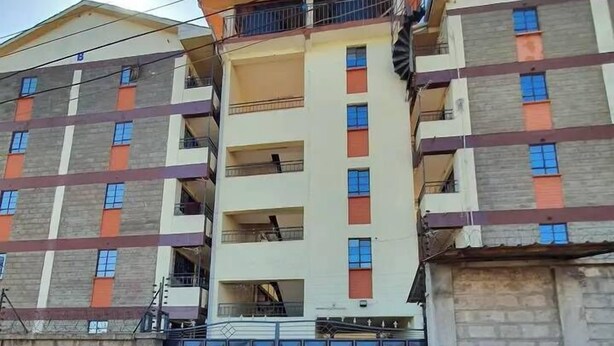 A multi-story building with a gated entrance, a satellite dish, and a brick wall. - Mountain view Spring (Nairobi)