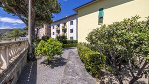 A pathway leading to a building with a balcony, surrounded by greenery and a clear sky. - Next to the Beach by Wonderful Italy (Ospedaletti)