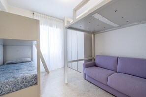 Un dormitorio con una cama individual, un sofá y un armario.