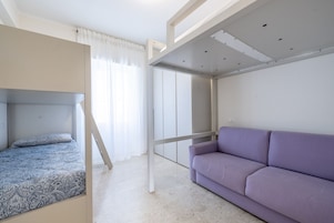 A bedroom with a bunk bed, a sofa, and a wardrobe.