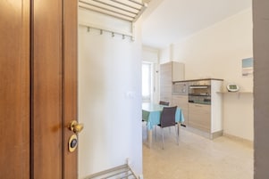 Una cocina compacta equipada con microondas, horno y un reloj en la pared.