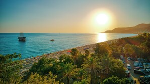 Una playa con un bote, sombrillas y coches.