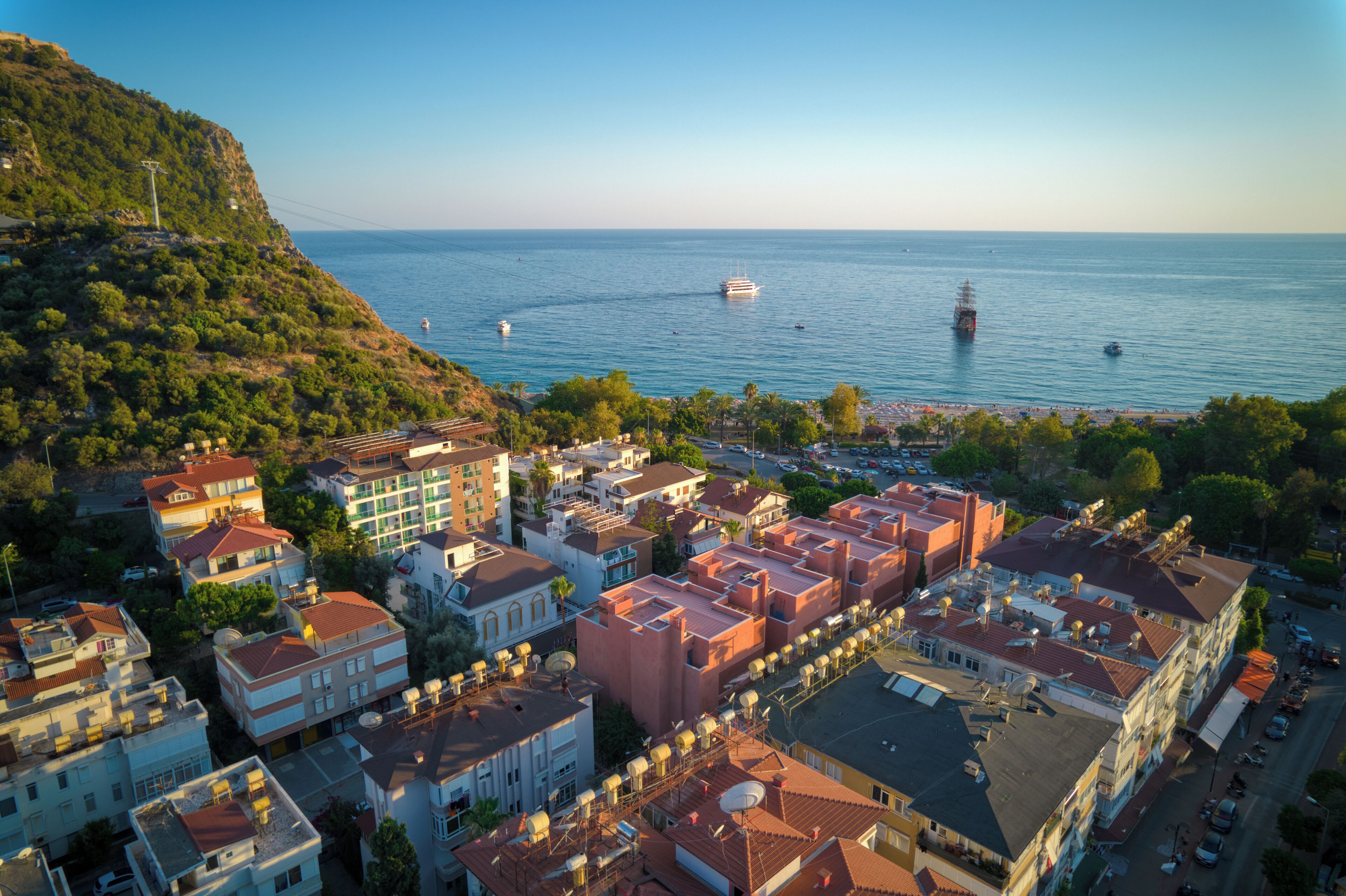 An aerial view of a coastal town with buildings, a beach, and boats on the water.