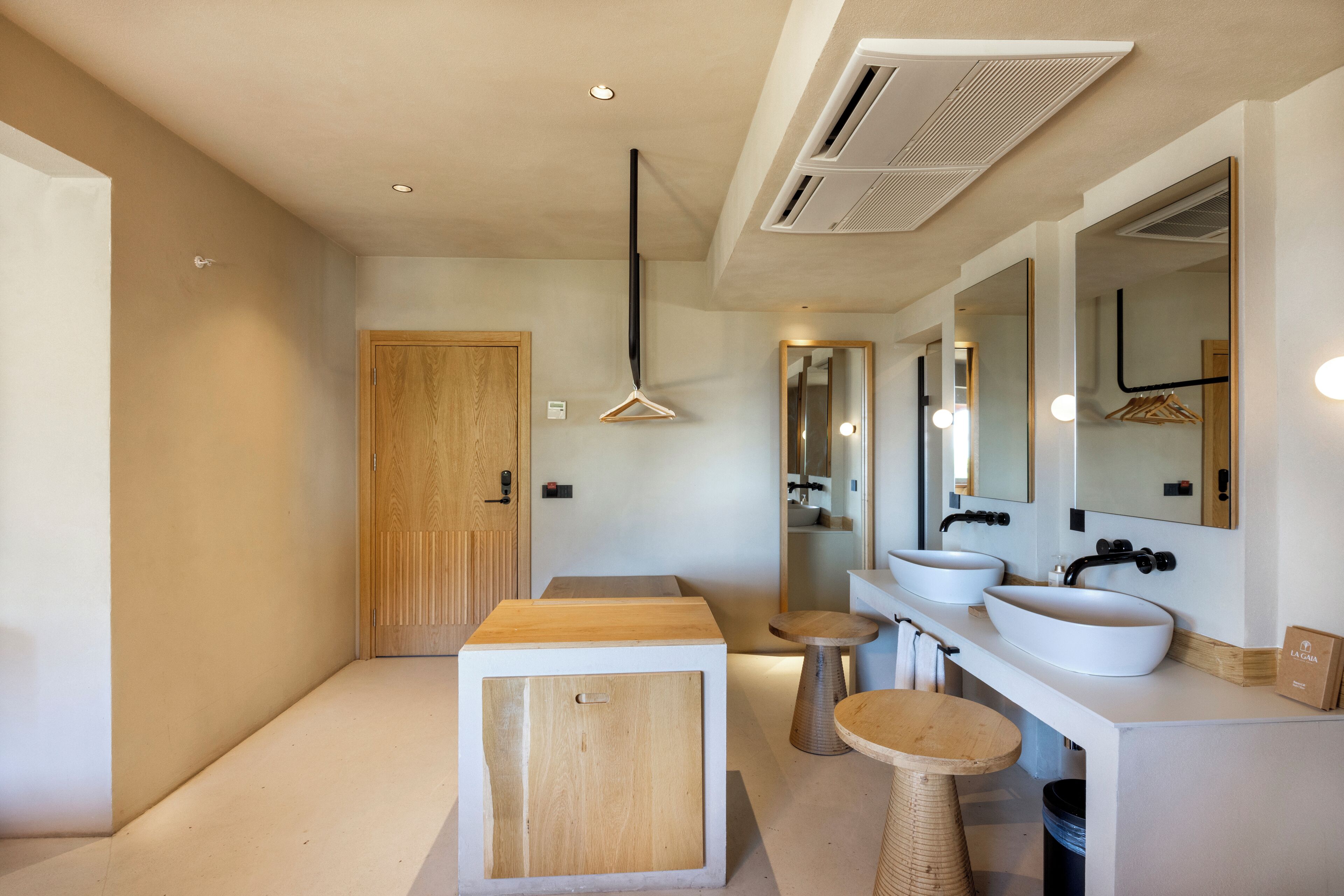 A modern bathroom with a wooden cabinet, two sinks, a mirror, and a hanging shower curtain.
