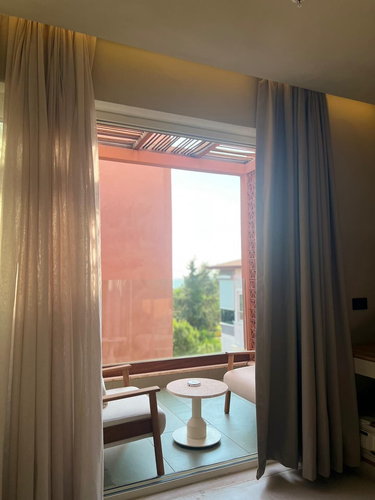 A room with a view through a window, a small round table, and a chair.