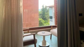 A room with a view through a window, a small round table, and a chair.