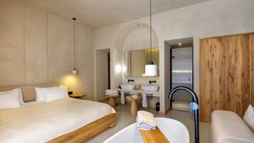 Habitación de hotel moderna con una cama grande, un sofá independiente, una bañera, un tocador con espejo y un armario de madera.