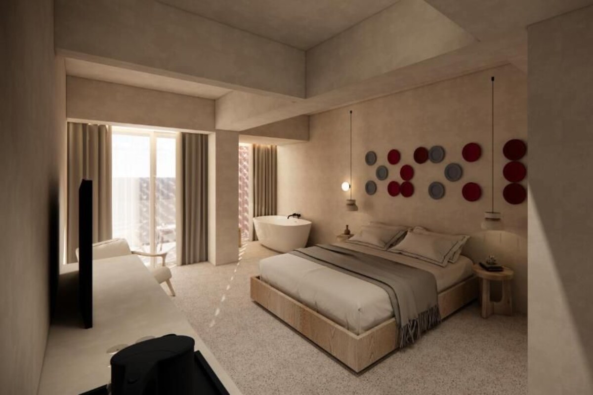 A modern bedroom with a large bed, a bedside table, a wall-mounted light fixture, and a view of the outdoors.
