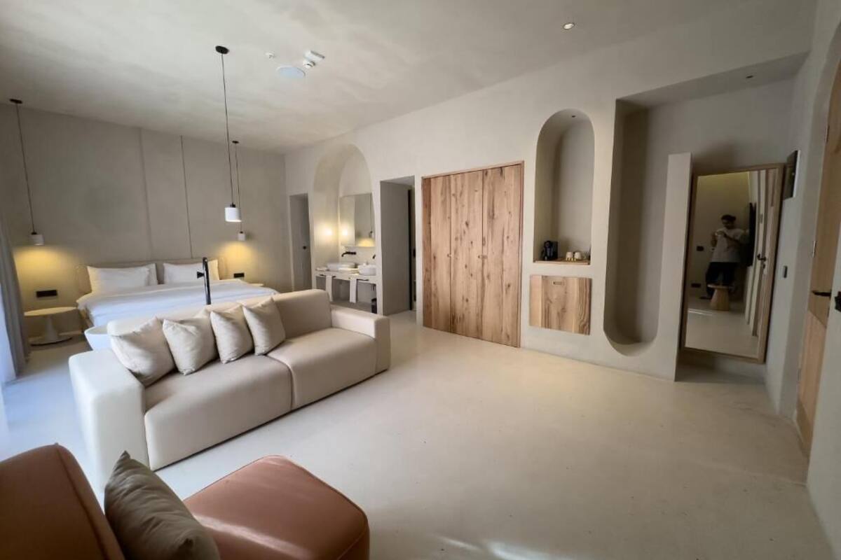 Een moderne slaapkamer met een groot bed, een sofa, een houten garderobe en een spiegel.