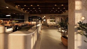 Una cocina moderna con una isla central, electrodomésticos integrados y una zona de estar con mesas y sillas.