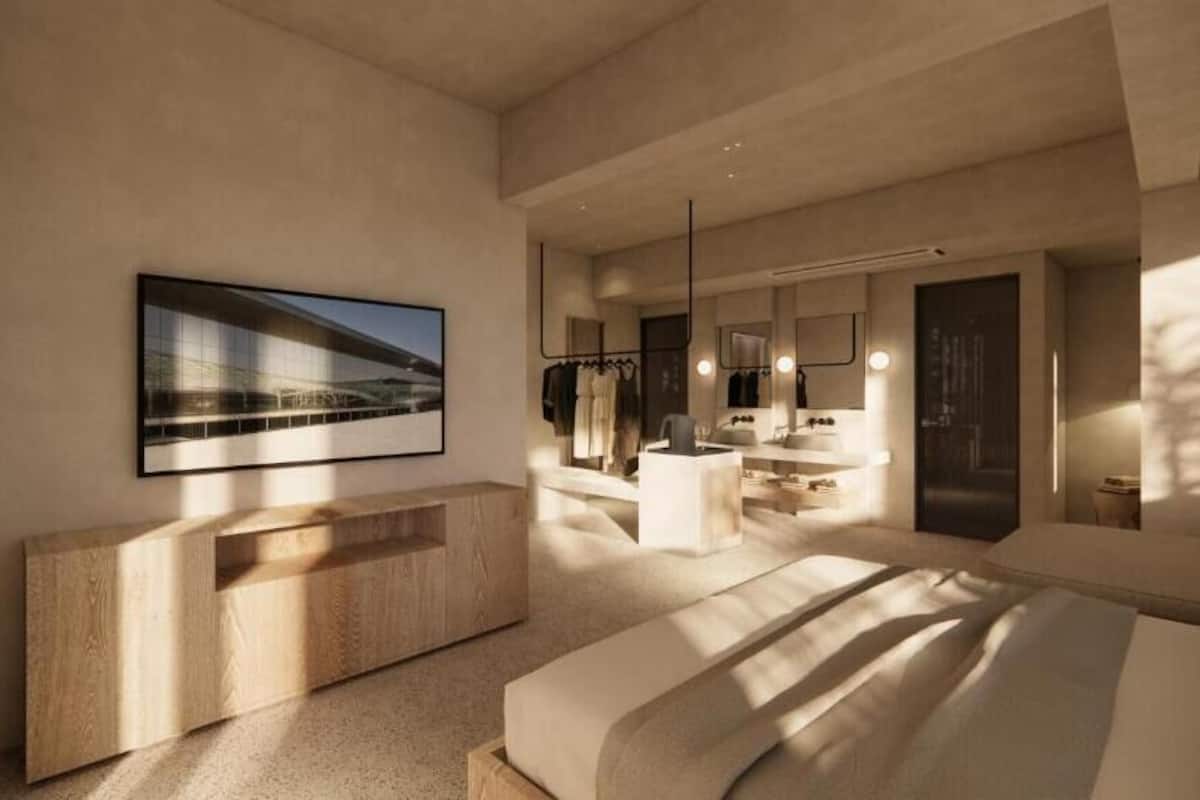 Un dormitorio moderno con una cama grande, una consola de madera, un baño con espejo y lavamanos, y un cuadro enmarcado en la pared.