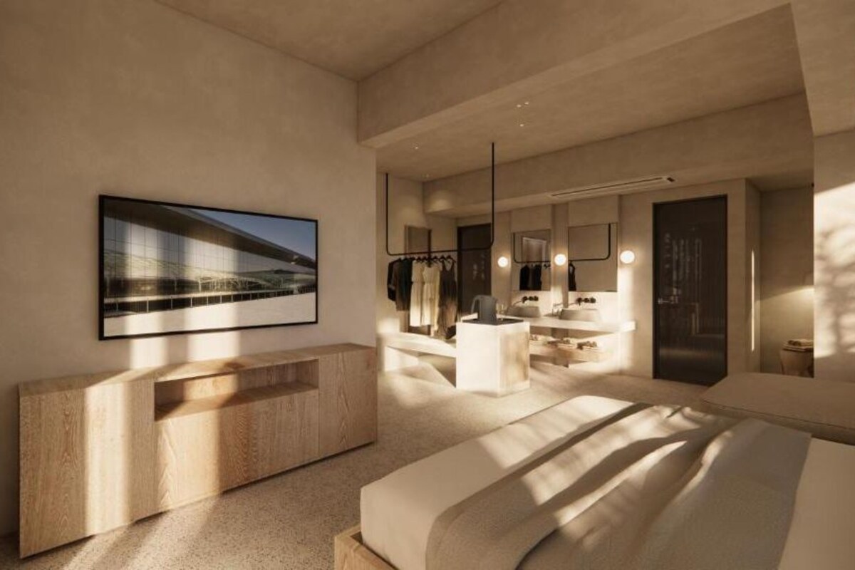 A modern bedroom with a large bed, a wooden console, a bathroom with a mirror and sink, and a framed picture on the wall.
