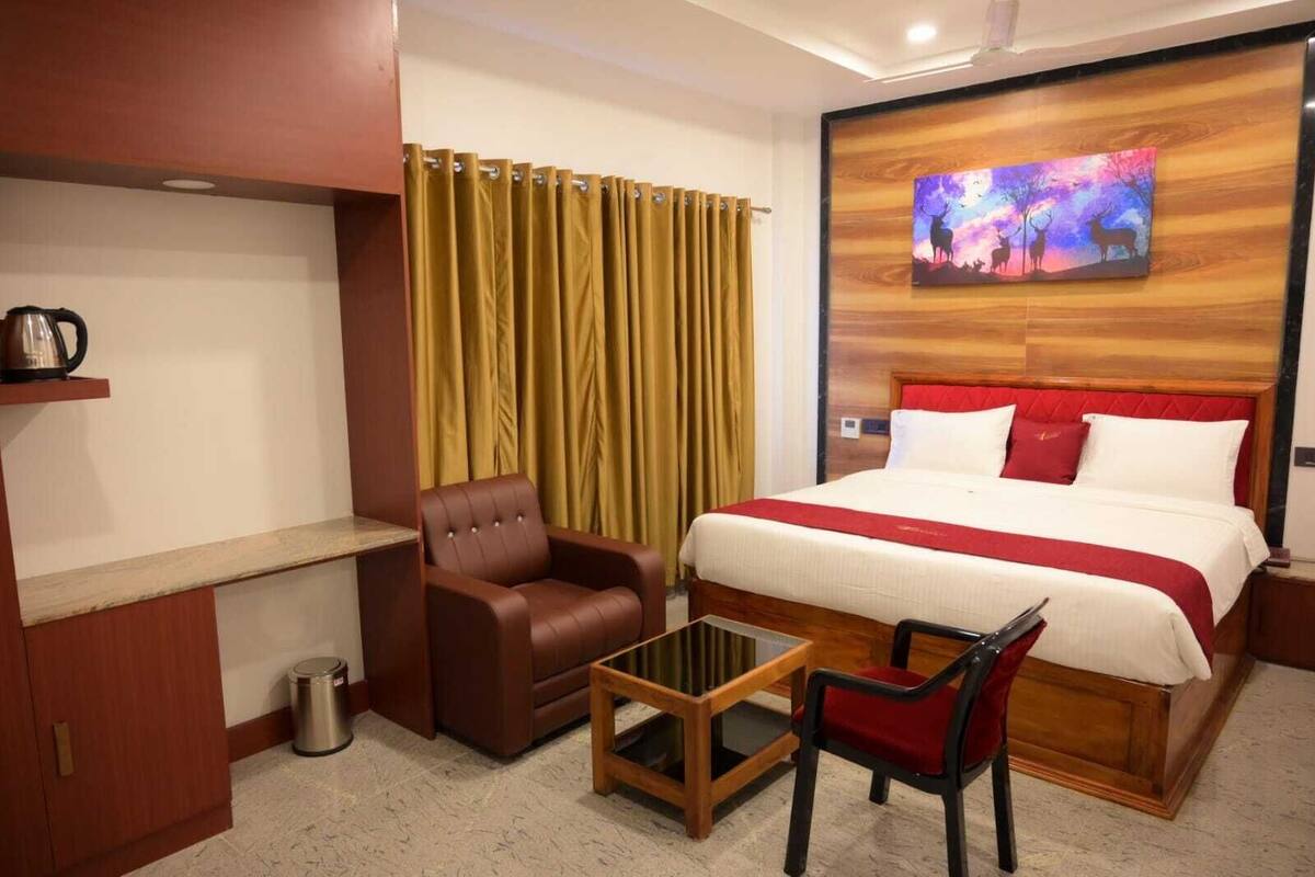 Een hotelkamer met een bed, een bureau, een stoel, een klein tafeltje en een schilderij aan de muur.
