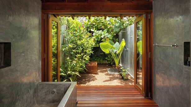 A wooden deck leading to a glass door, surrounded by lush greenery and a small garden area. - Villa Thamburu (Bentota)