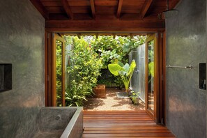 A wooden deck leading to a glass door, surrounded by lush greenery and a small garden area. - Villa Thamburu (Bentota)