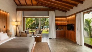 A modern hotel room with a large bed, a seating area with a coffee table, a TV, and a view of the outdoors. - Villa Thamburu (Bentota)