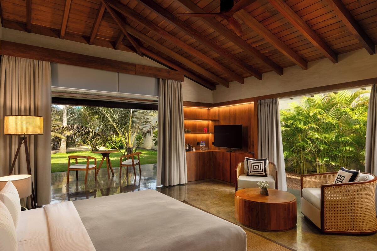 A spacious room with a large bed, a dining area, a kitchen, and a TV.