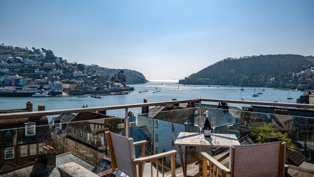 A terrace with a table and chairs overlooking a harbor with boats, buildings on hills, and a clear sky. - Dartmouth Hideaway, Large Roof Terrace & Views (Dartmouth)