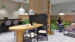 A modern office space with a wooden conference table, black chairs, and pendant lighting.
