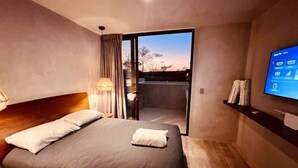 Ett modernt hotellrum med en stor säng, en TV och en balkong med utsikt.