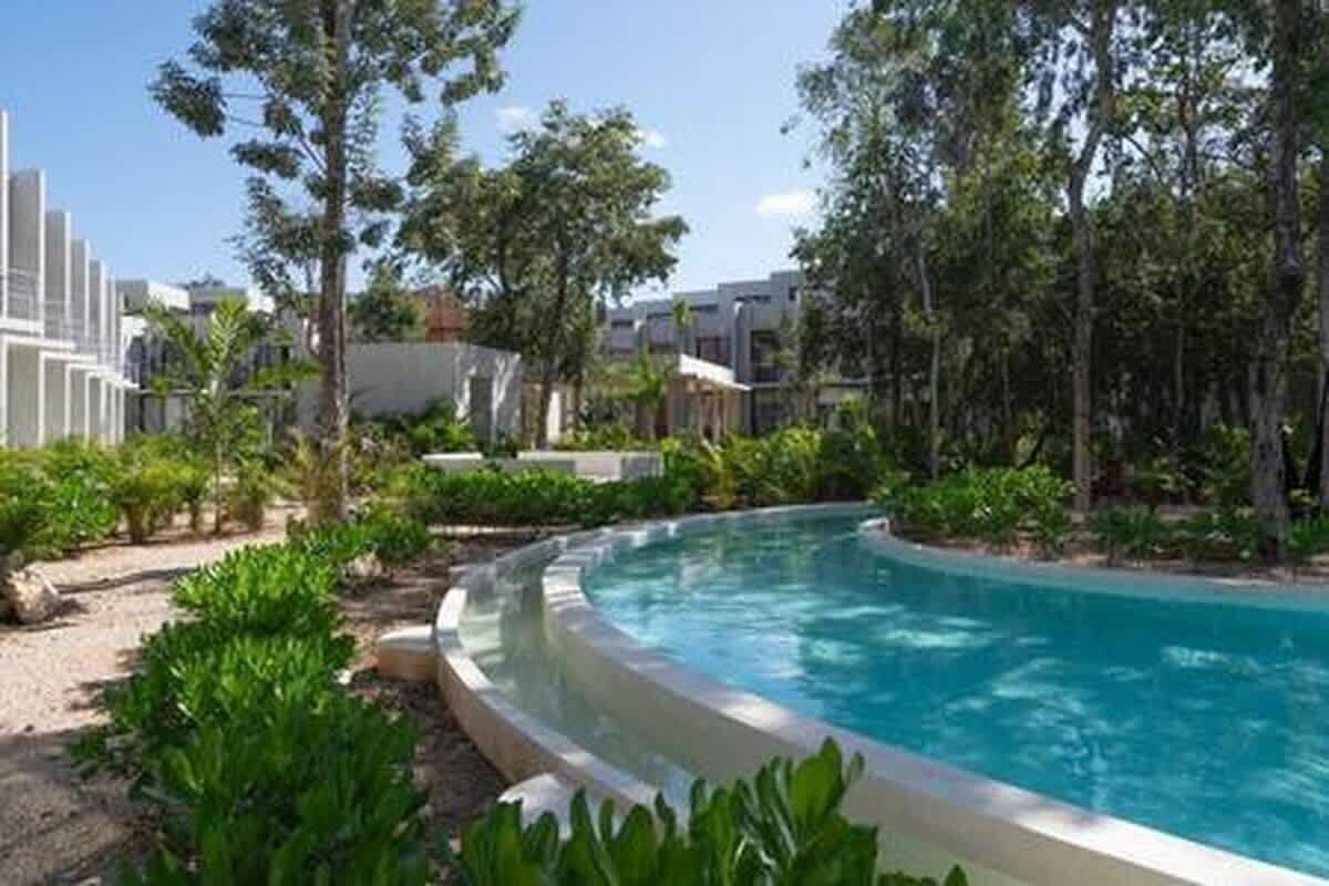 Ein Schwimmbad, umgeben von viel Grün und modernen Gebäuden.