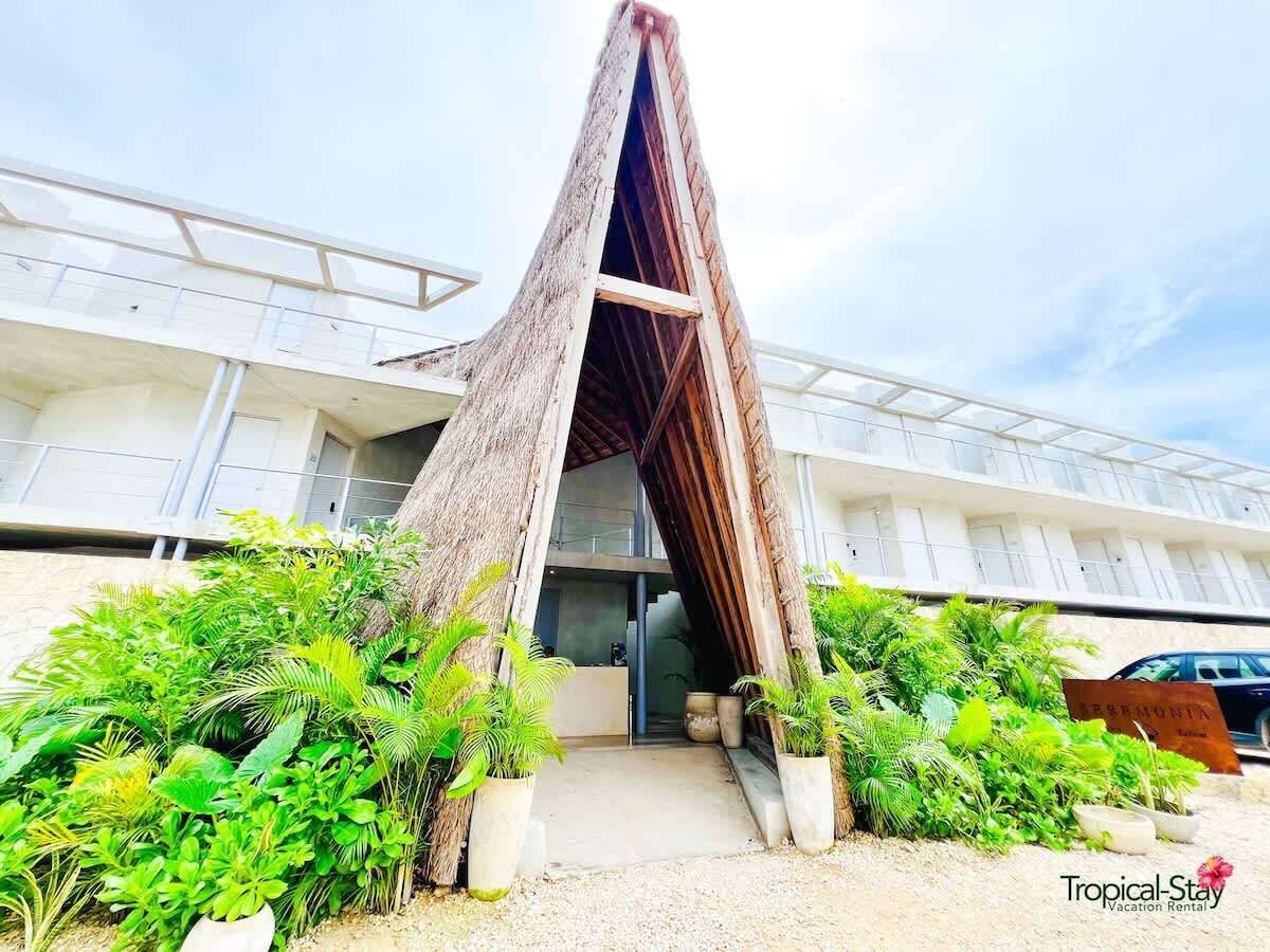 Un bâtiment doté d’une structure de toit inclinée unique, entouré d’une végétation luxuriante.