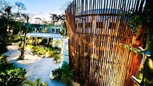 A garden area with a wooden fence, a pathway, and a small bridge. - Private Pool & Grill 2 Bedroom Apartment 417Selva (Tulum)