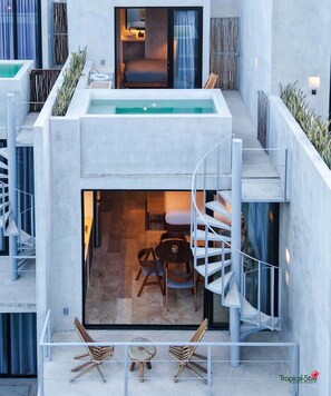 A modern building with a rooftop pool, a spiral staircase, and a small seating area with chairs.