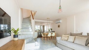 A modern living room with a staircase, a dining area, and a kitchen. - 3 BD house with Private Solarium and patio (Cordoba)